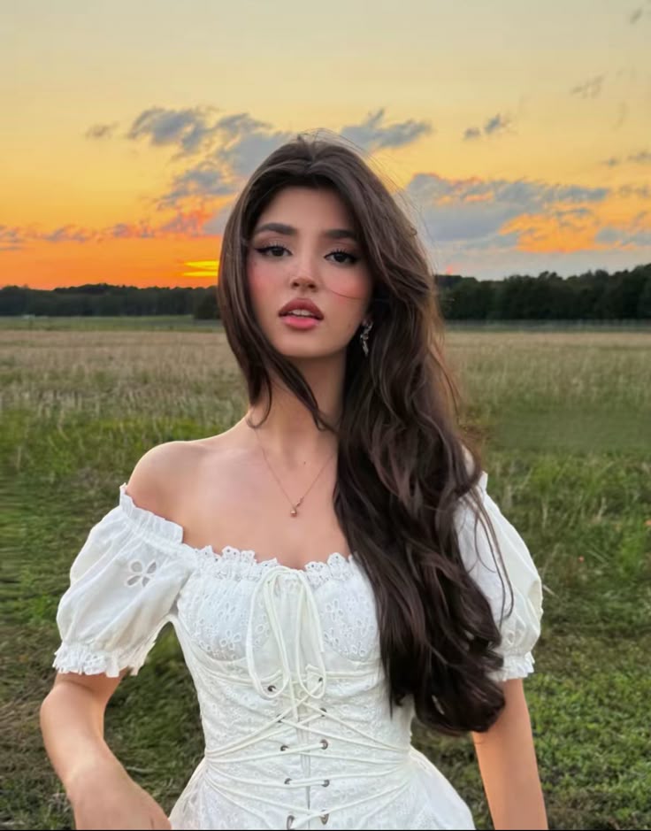This may contain: a woman in a white dress is posing for a photo with her hands on her hips